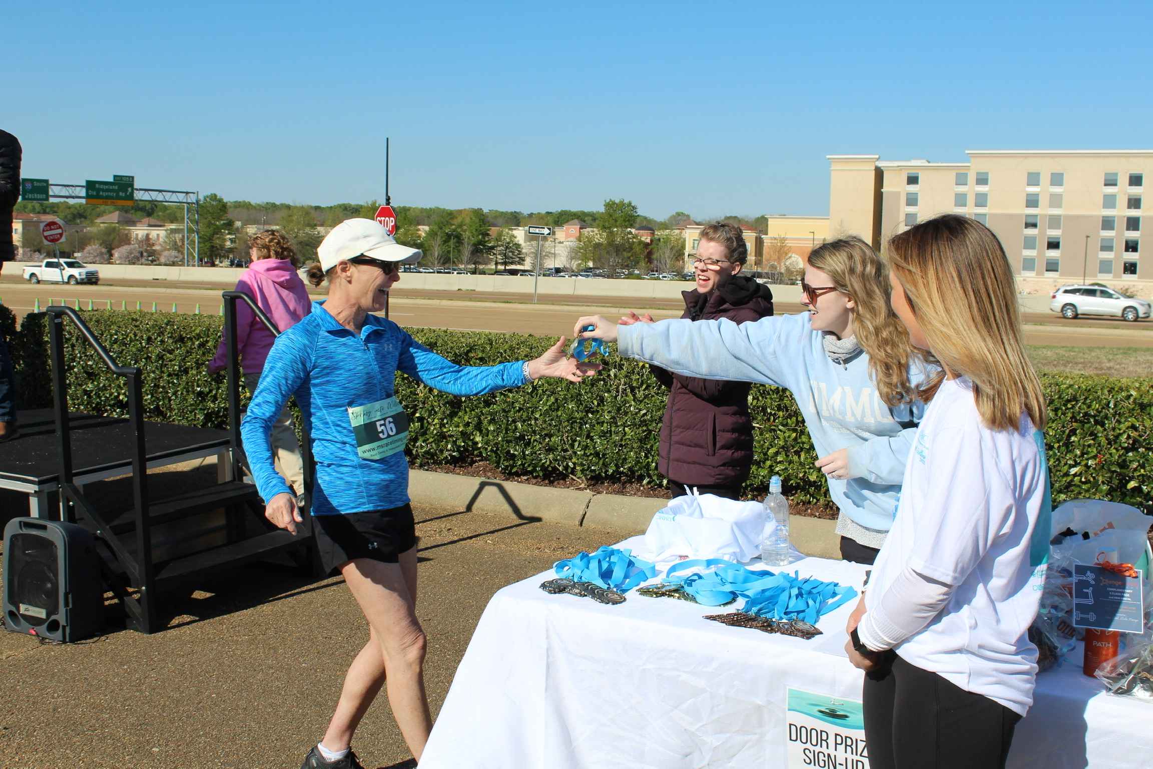 Medal Recipient reaches for medal from attendants at a table.